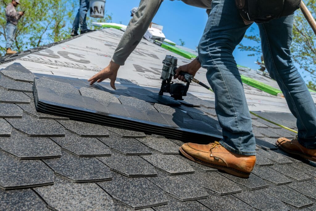 Premier Remodelers Roofer using nail gun for shingle installation on residential roof.